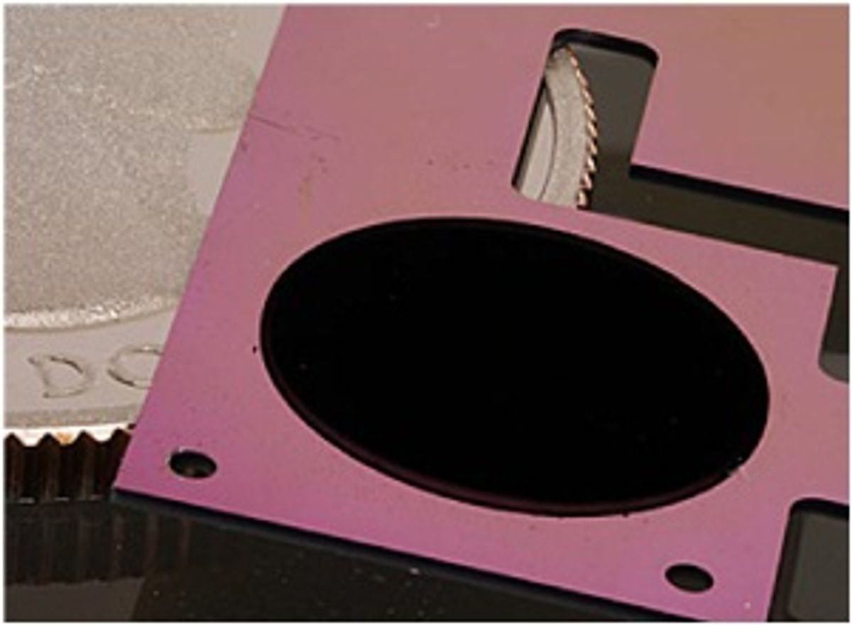 The circular patch of carbon nanotubes on a pink silicon backing is one component of NIST’s new cryogenic radiometer, shown with a quarter for scale.