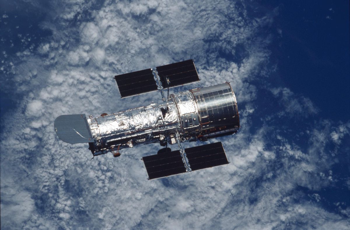 The Hubble Space Telescope, with clouds in the background, seen during a space shuttle servicing mission in 2002.