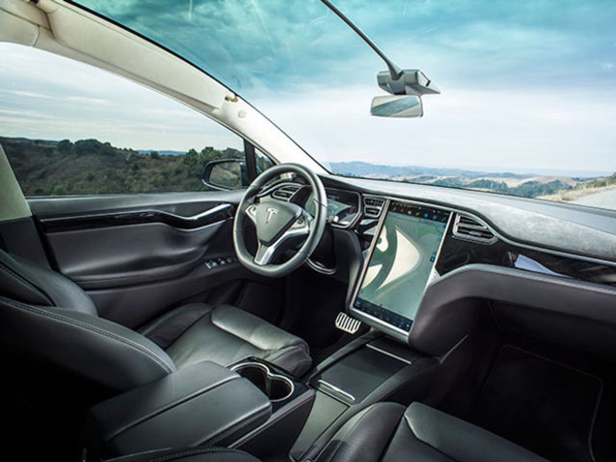 The interior of a Tesla car, with a large display screen on the dashboard