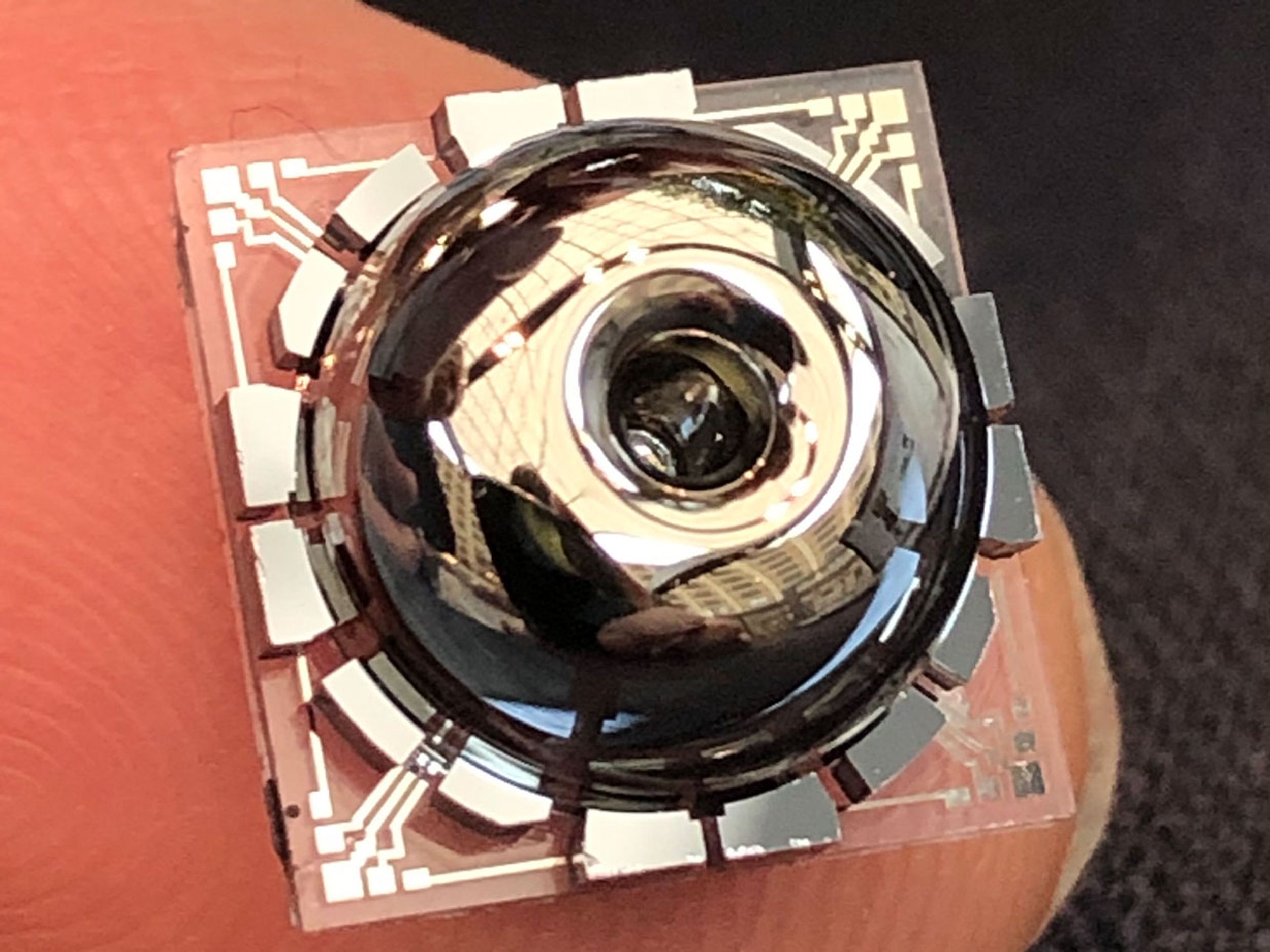 The new resonator and electrodes, on a finger for scale. The resonator is almost perfectly symmetrical, made of nearly-pure glass. This enables it to vibrate for long periods, similar to the ringing of a wine glass.