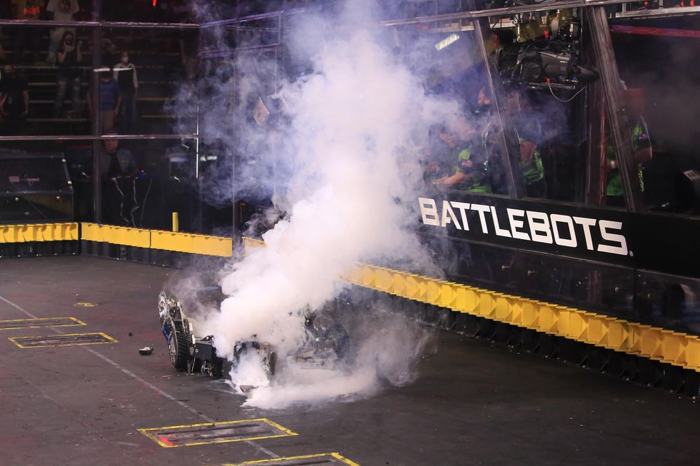 The remains of a shiny wheeled robot is almost completely obscured by white smoke.