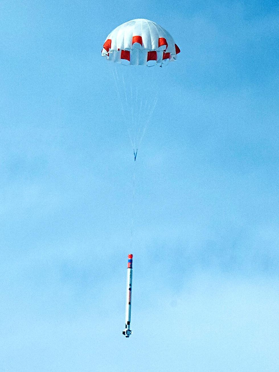 The right photo shows the rocket descending underneath a white-and-orange parachute.