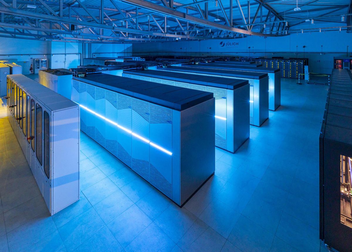 This image shows several rows of computer racks, which give off an eerie blue glow.