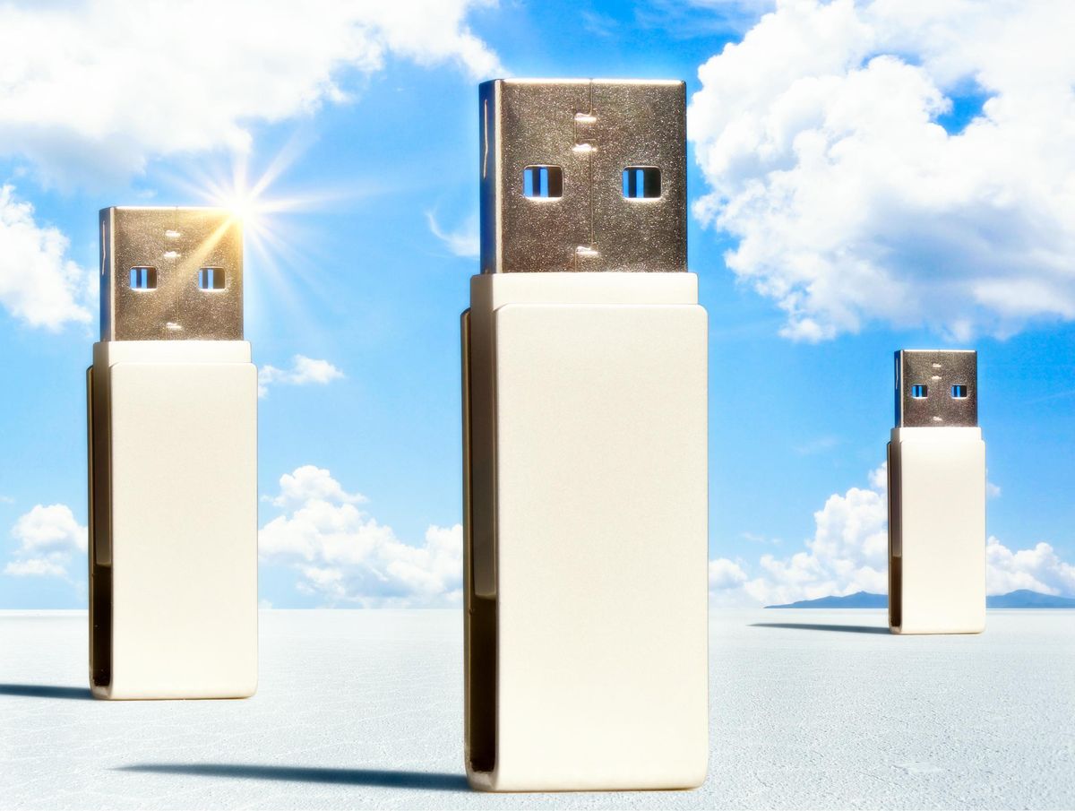 Three monolithic thumb drives stand in a white landscape with blue sky and clouds behind them.