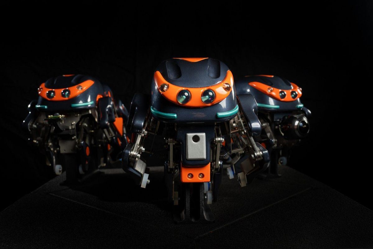 Three orange and black robots that look like mechanical spiders