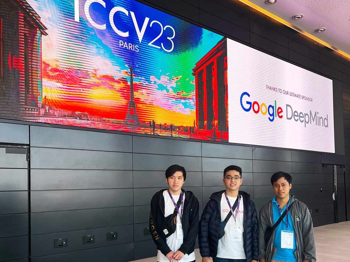 three young men standing underneath a large sign that reads “ICCV23 Paris” and “Google DeepMind”