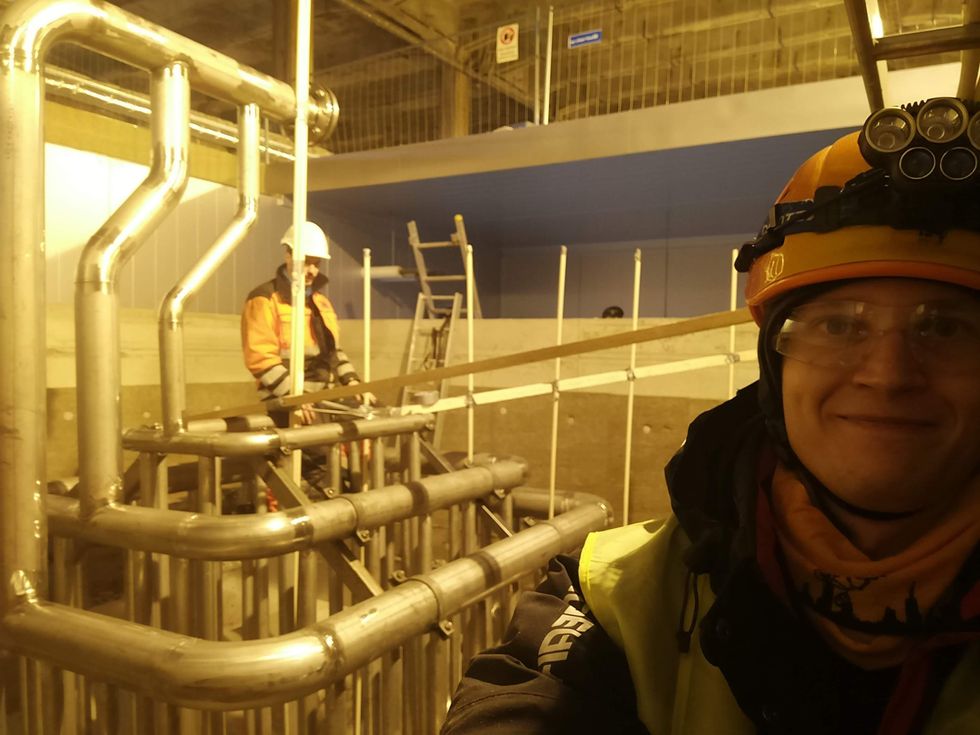 Tommi Eronen dressed in construction gear stands near the company's heat-storage system.
