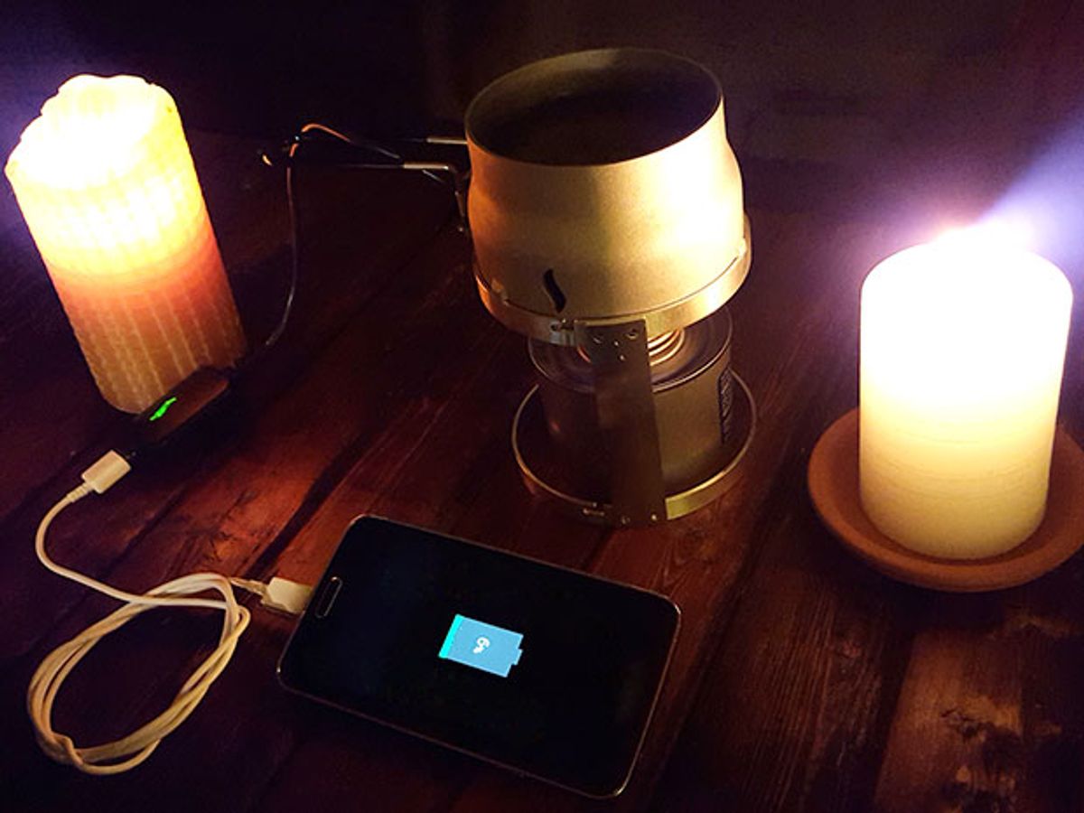 Two candles, a sterno can, and a smartphone connected to a charging device.