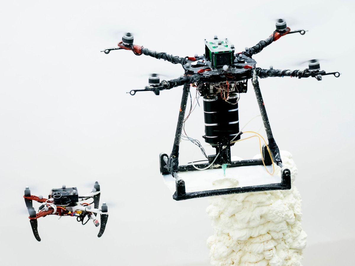 two drone flying in the air, one printing a 3d structure