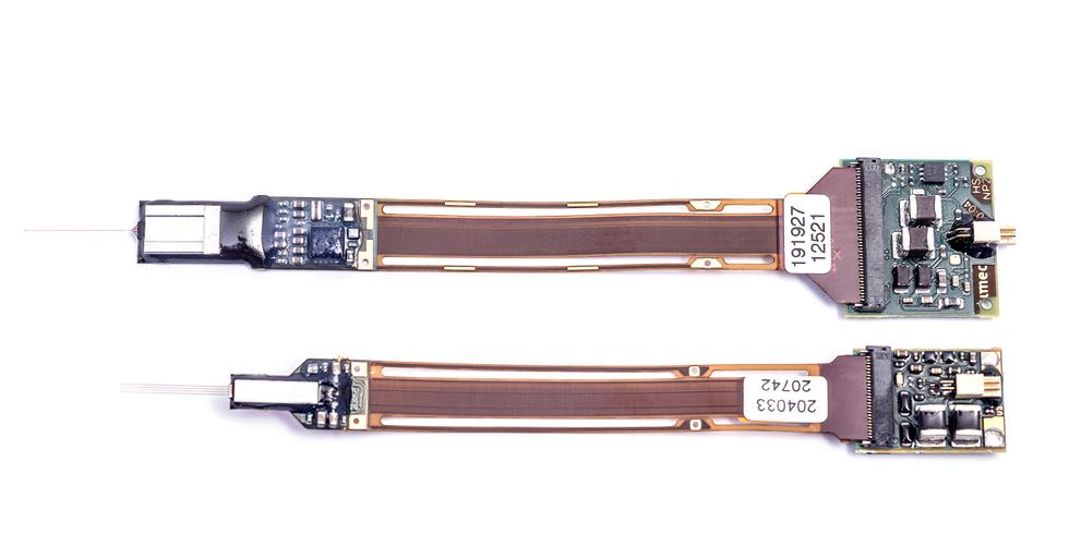 Two long and slender devices have delicate wires at left, tape-like connectors at center, and circuit boards at right. The top device is bigger and has one delicate wire, the bottom device is smaller and has four delicate wires.