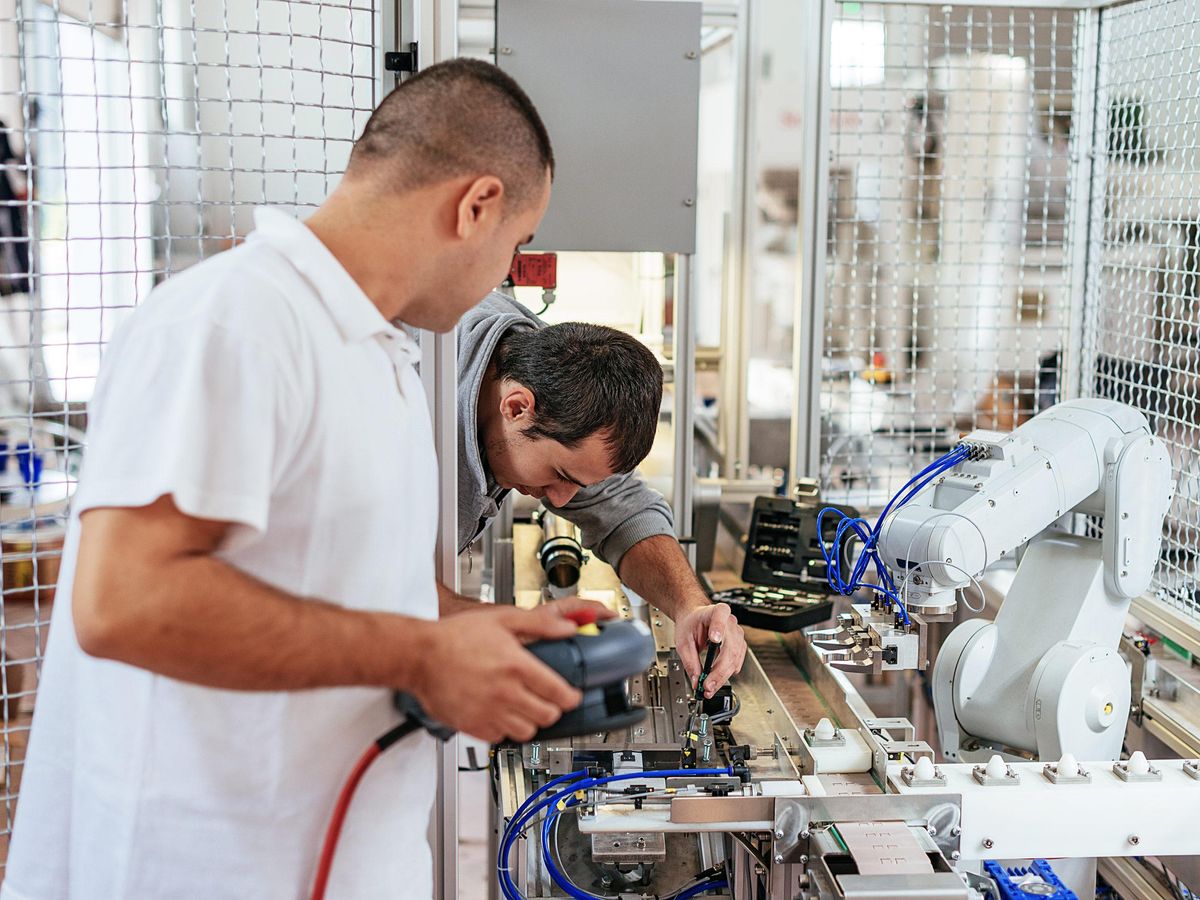 Two men adjust settings on a product line
