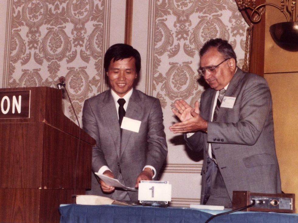Two men stand in a conference room behind a podium.