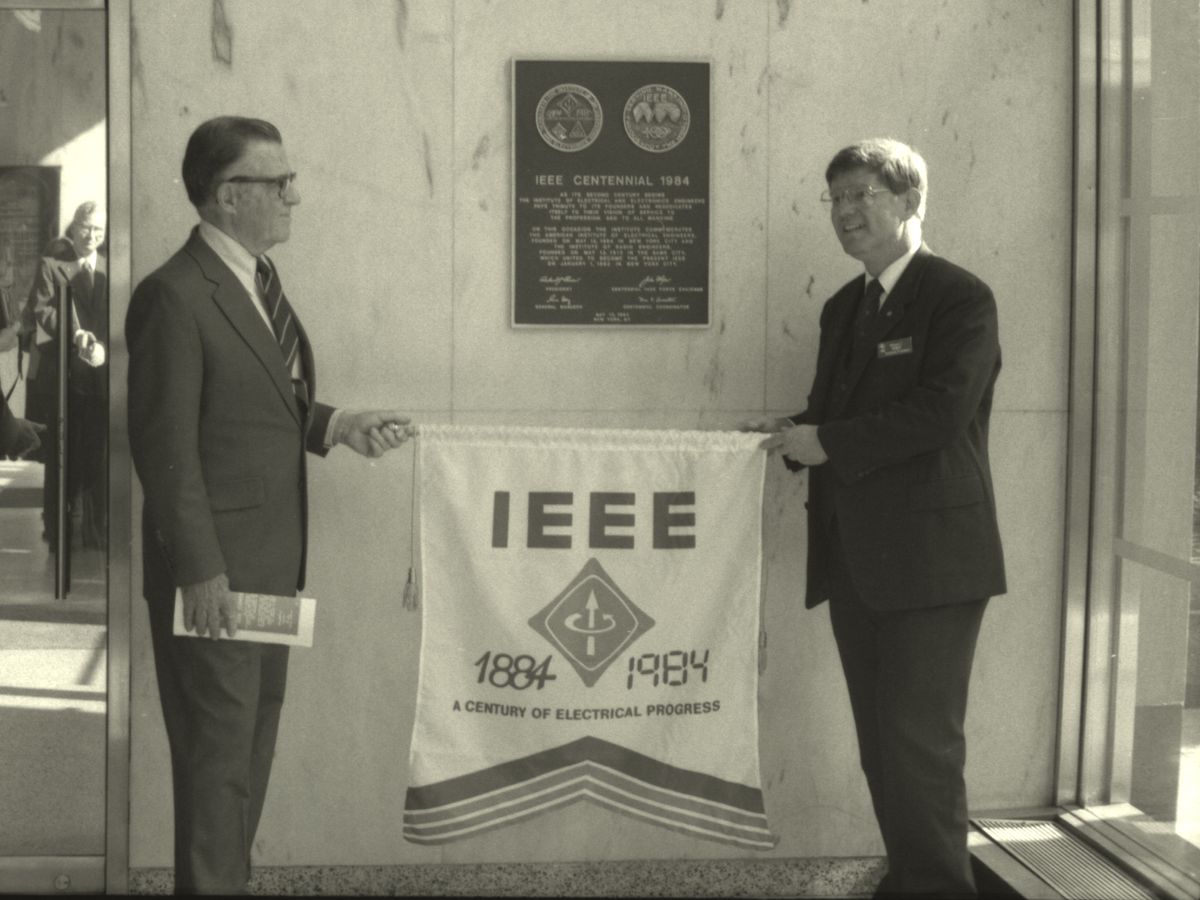 Two men standing by a plaque.