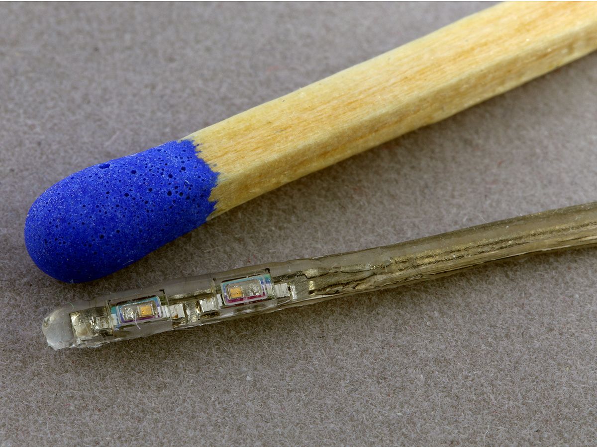 Two of the vertical cavity surface-emitting lasers used in a new optical cochlear implant are shown here next to a matchstick. Each laser rests within a sapphire box.