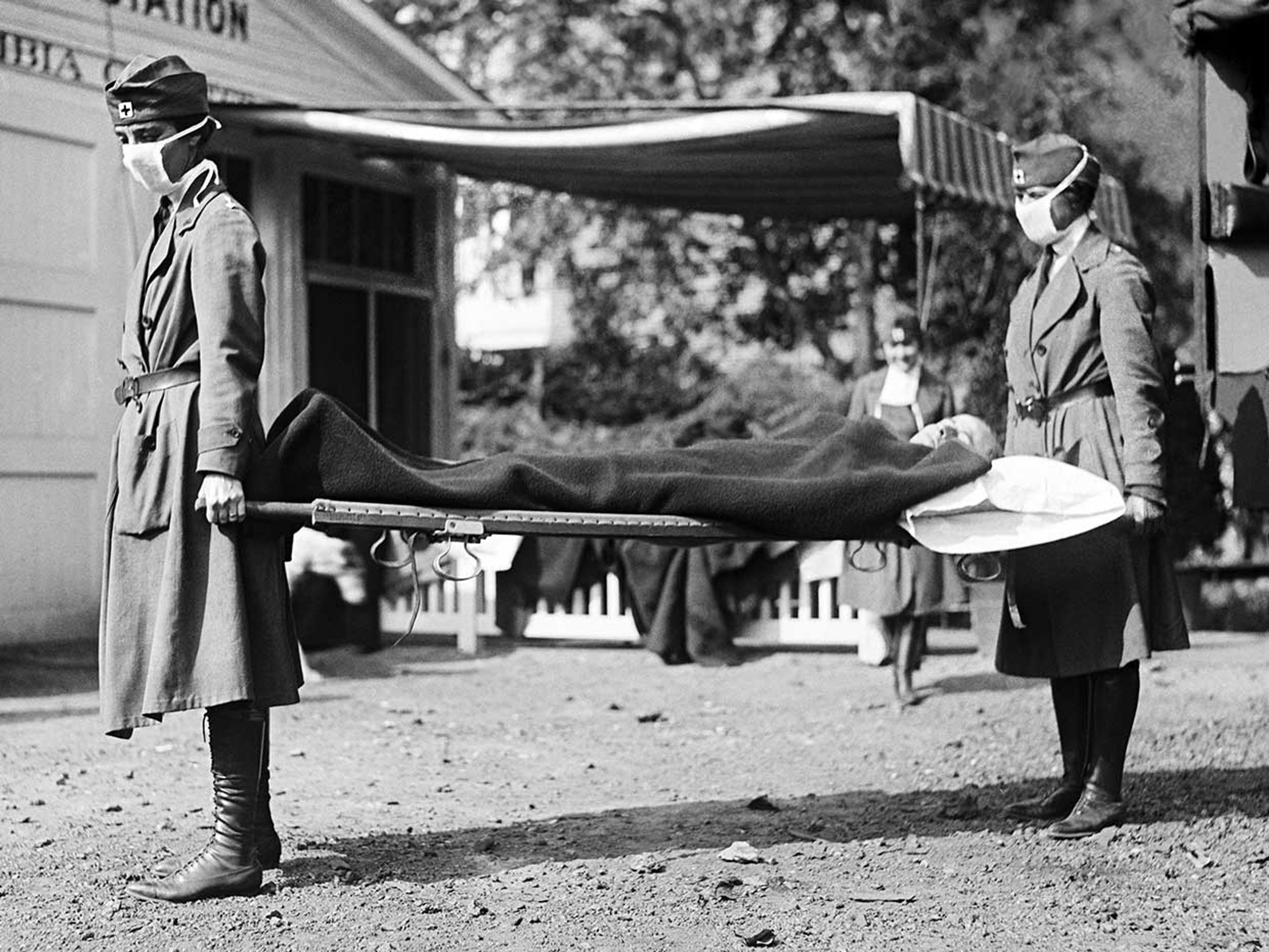 Two Red Cross nurses with a person on a stretcher during a demonstration at the Red Cross Emergency Ambulance Station during the influenza pandemic of 1918-1920, Washington DC, 1918.