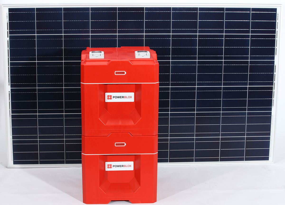 Two red cube shaped Power-Blox units stacked one on top of the other, in front of a solar panel.