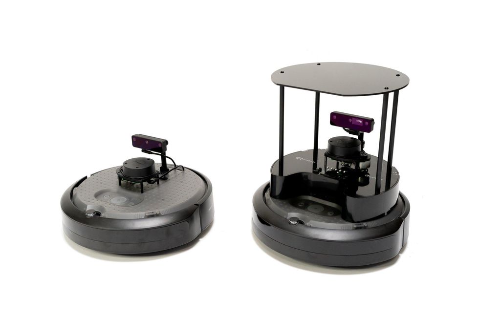 Two Turtlebot 4 robots, one shorter and another taller with a raised platform, both equipped with lidar and cameras, stand next to each other against a white background.