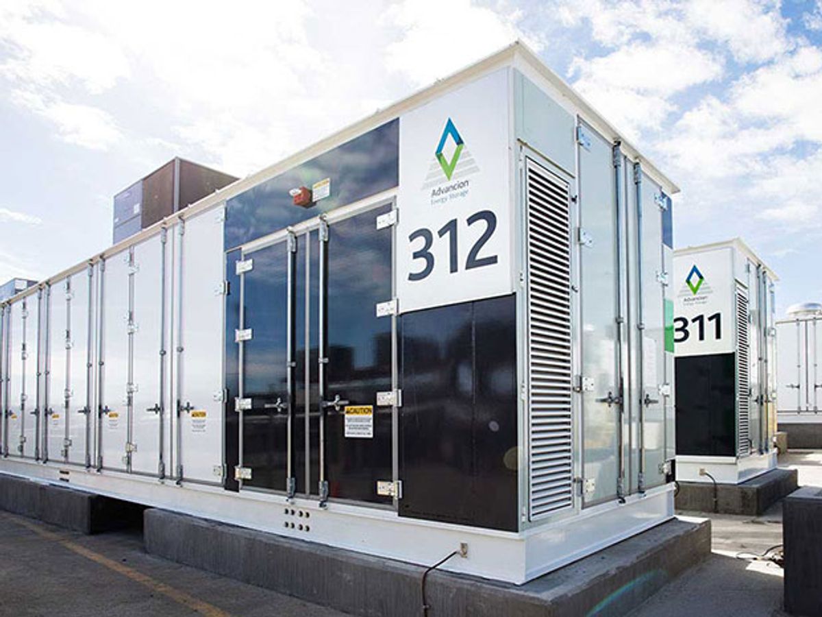 Two utility-scale energy storage units as deployed at a substation in California look like white and black cargo containers on cement pedestals