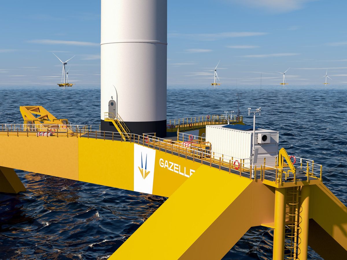 up close view of yellow structure sitting on ocean waters with whit wind turbines in the distance