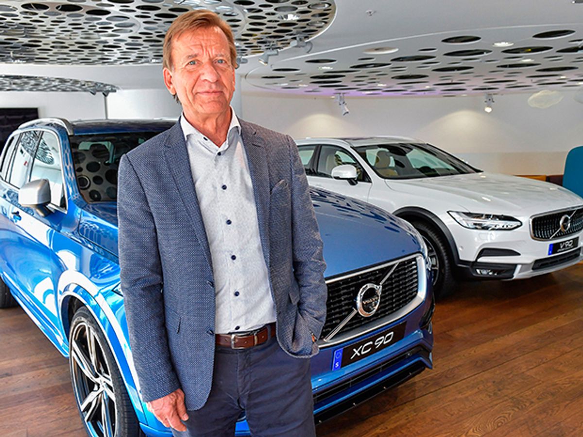 Volvo Cars CEO Hakan Samuelsson standing in front of a blue Volvo car and a white Volvo car