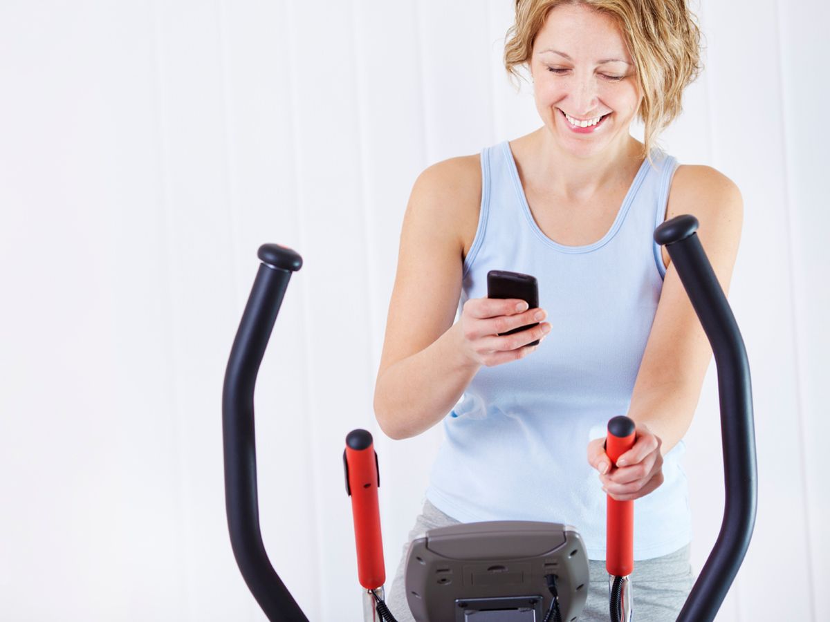 woman checking her mobile phone while working on exercise equipment. 