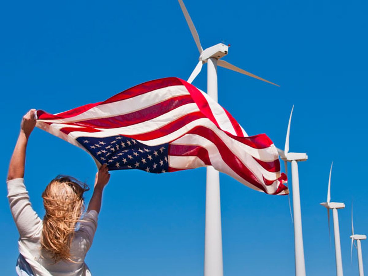 woman waves american flag near wind turbines