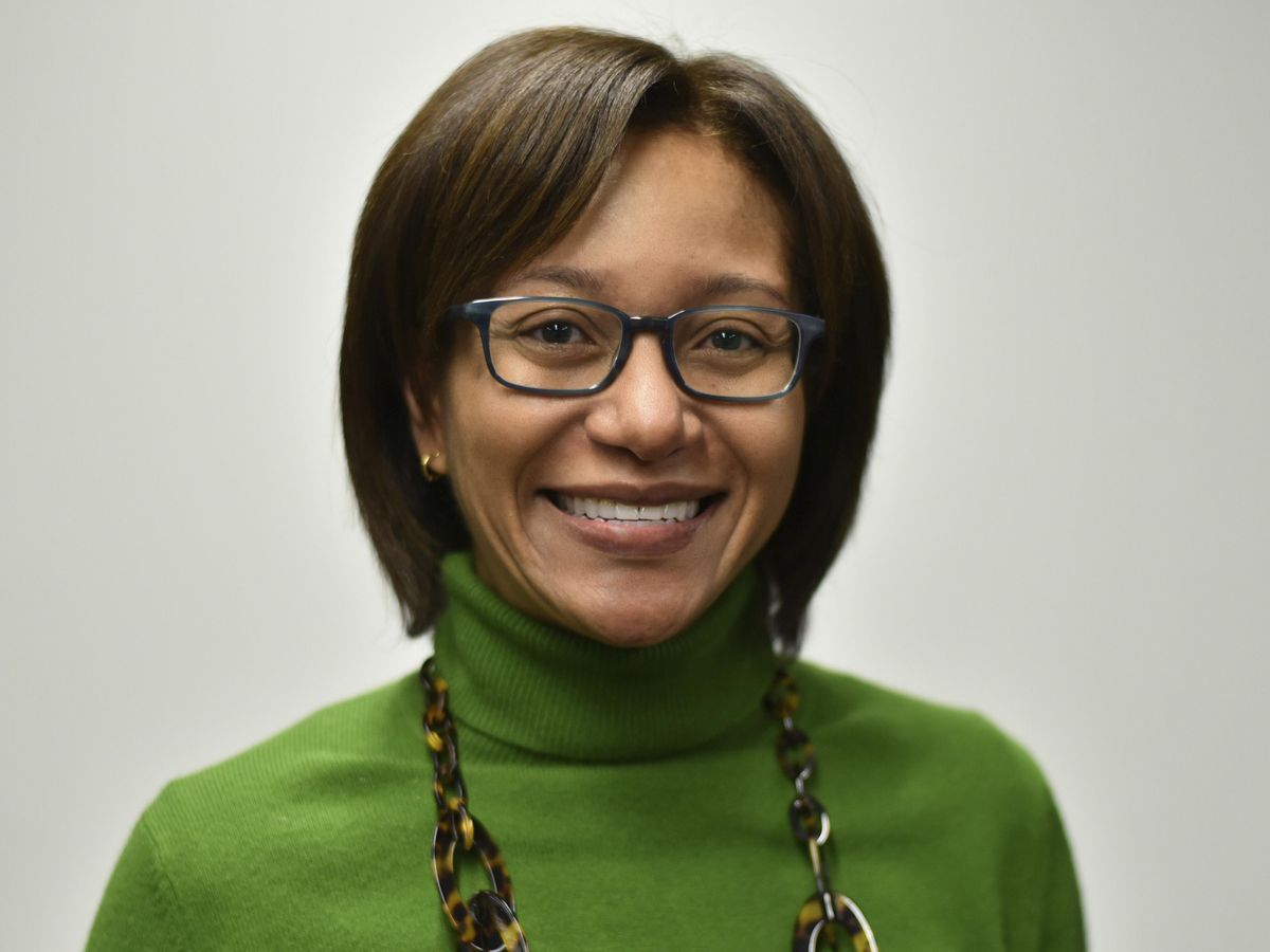 woman wearing glasses and green sweater smiling against a white background