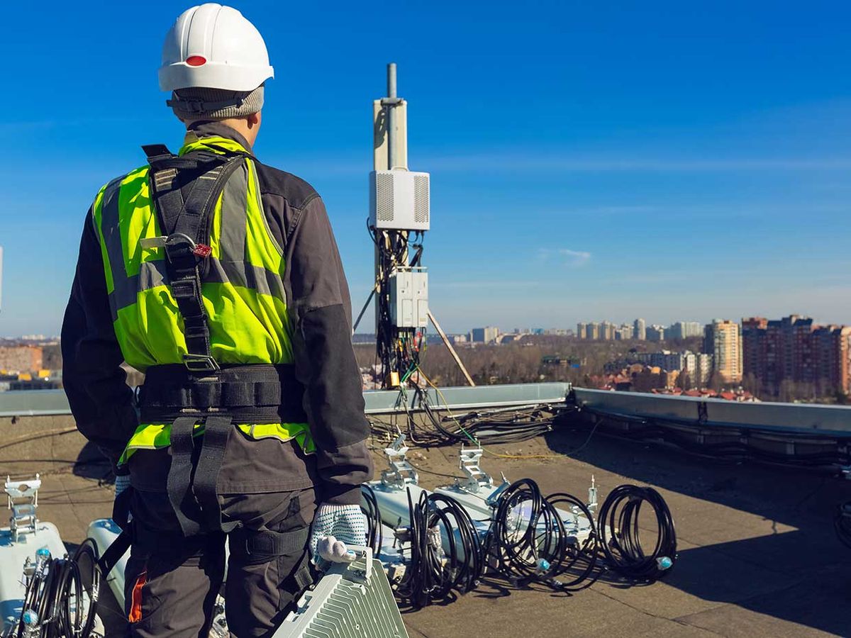 worker on a roof looking at wireless equipment
